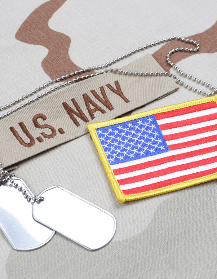 A u. S. Navy patch and dog tags on the ground