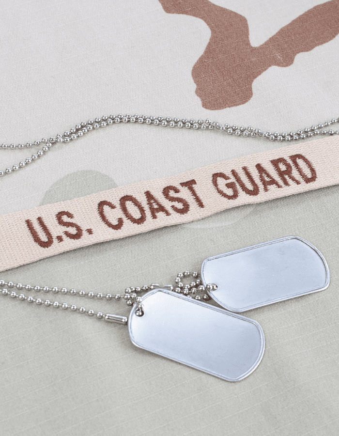 A couple of dog tags sitting on top of a u. S. Coast guard sign.