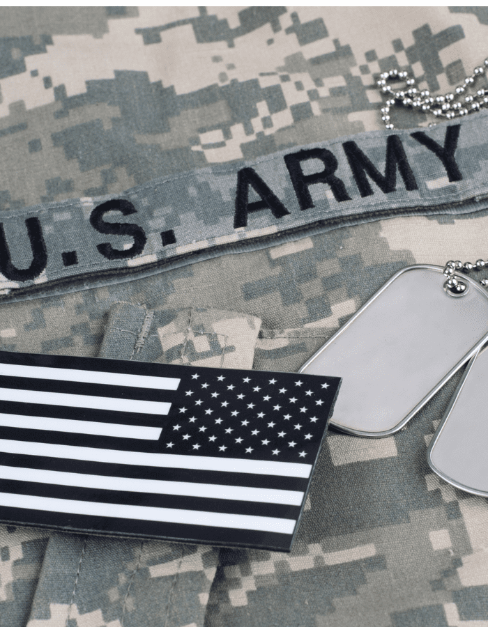 A us army patch, flag and dog tags on camouflage.