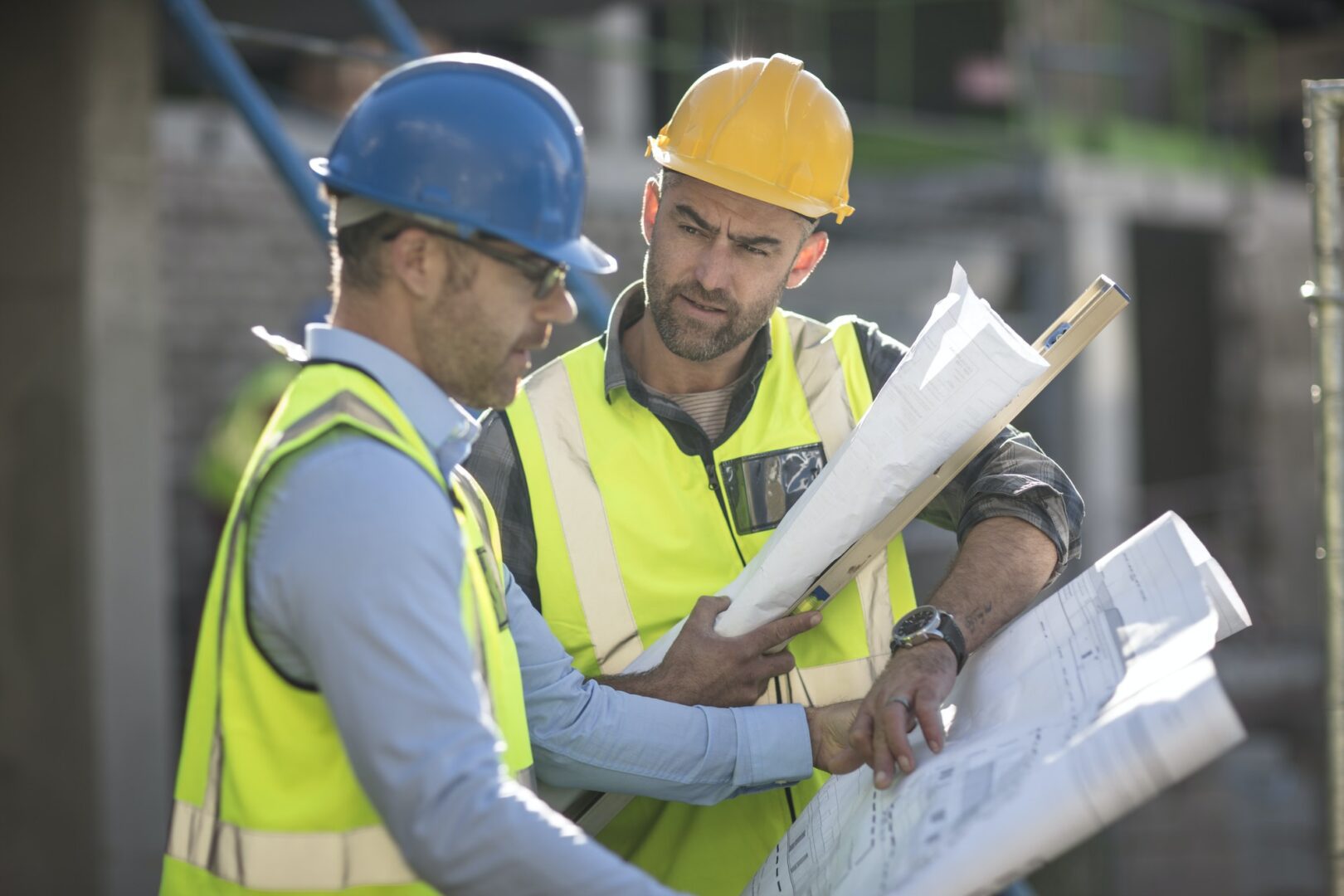 Two construction workers looking at a plan on top of a building.