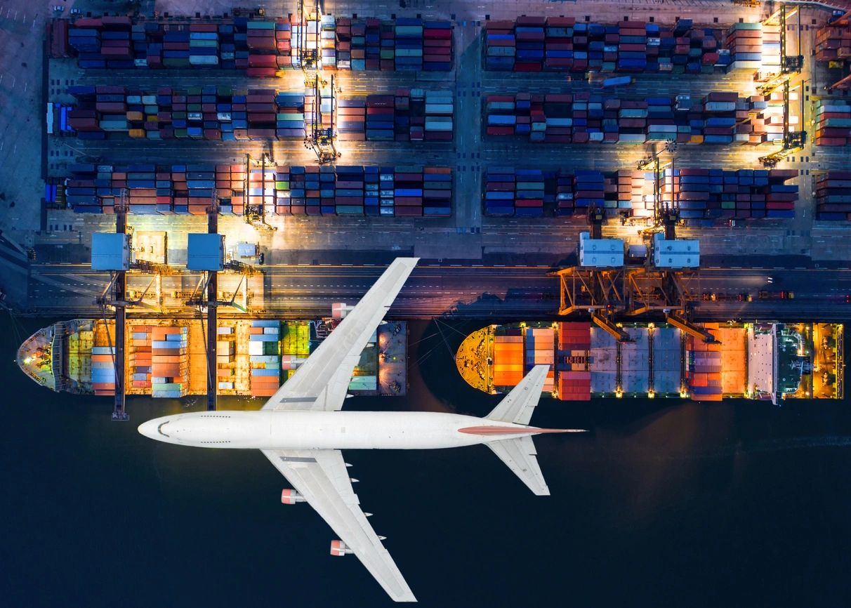 A large airplane flying over a lot of containers.